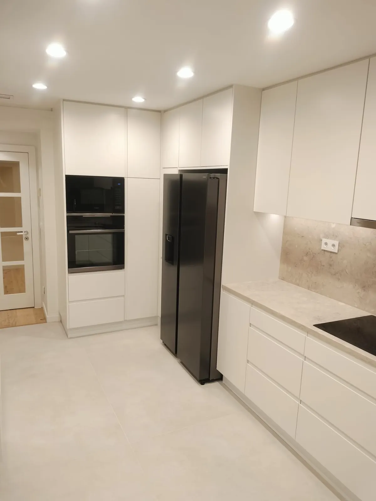 Cozinha remodelada pela D'talhe em Cascais, com móveis brancos e eletrodomésticos encastrados