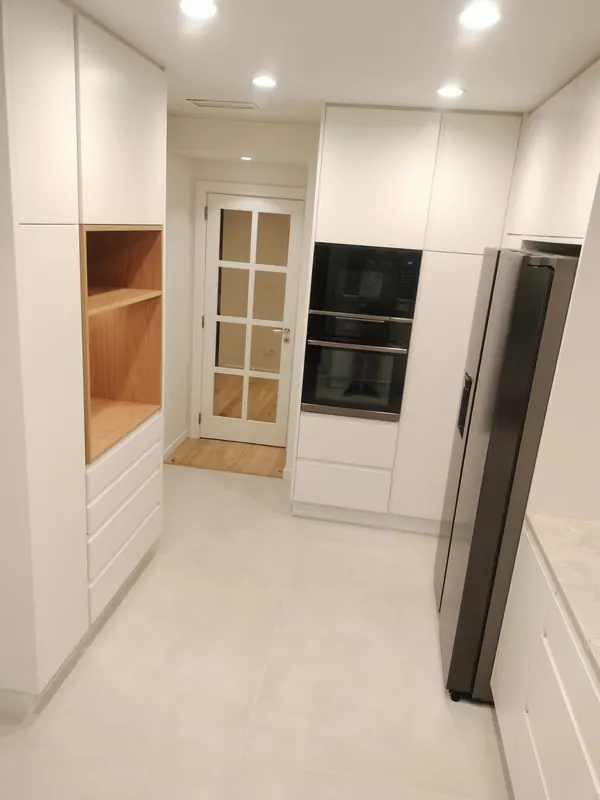 Cozinha branca remodelada em Cascais, com coluna de fornos