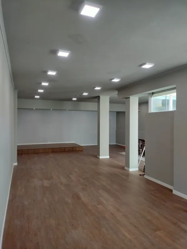 Remodelação de espaço comercial com pavimento em madeira e iluminação embutida